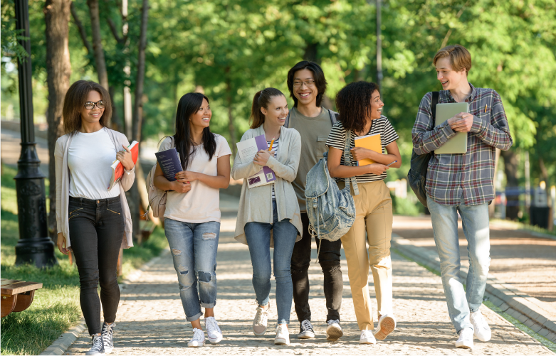 group of college students walking together smiling and holding class supplies and books