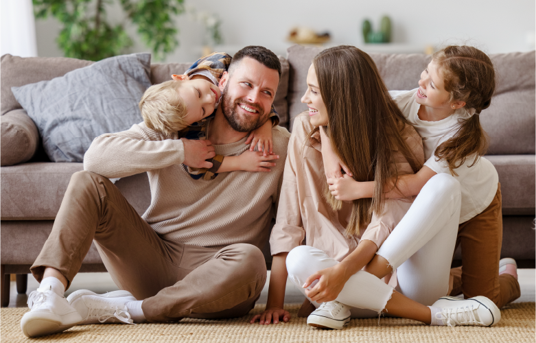 Family sitting with two young children on the floor in front of a couch