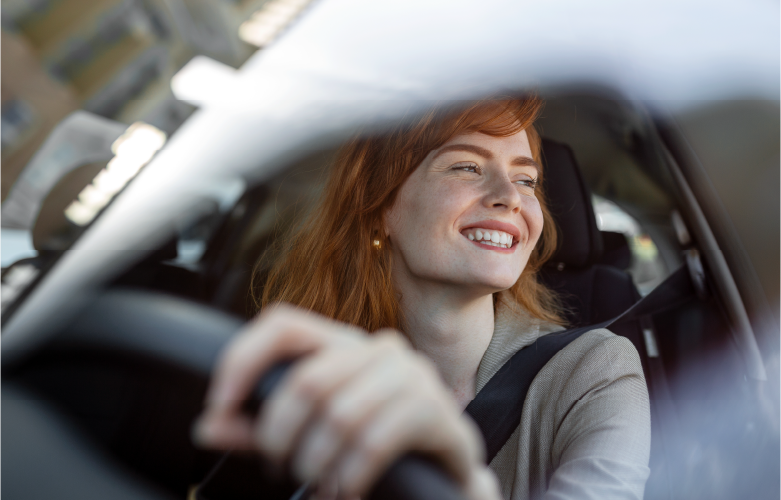 adult woman driving new car and smiling brightly