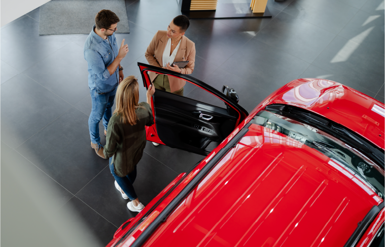 Arial view of young adult couple shopping for a new car in dealership showroom