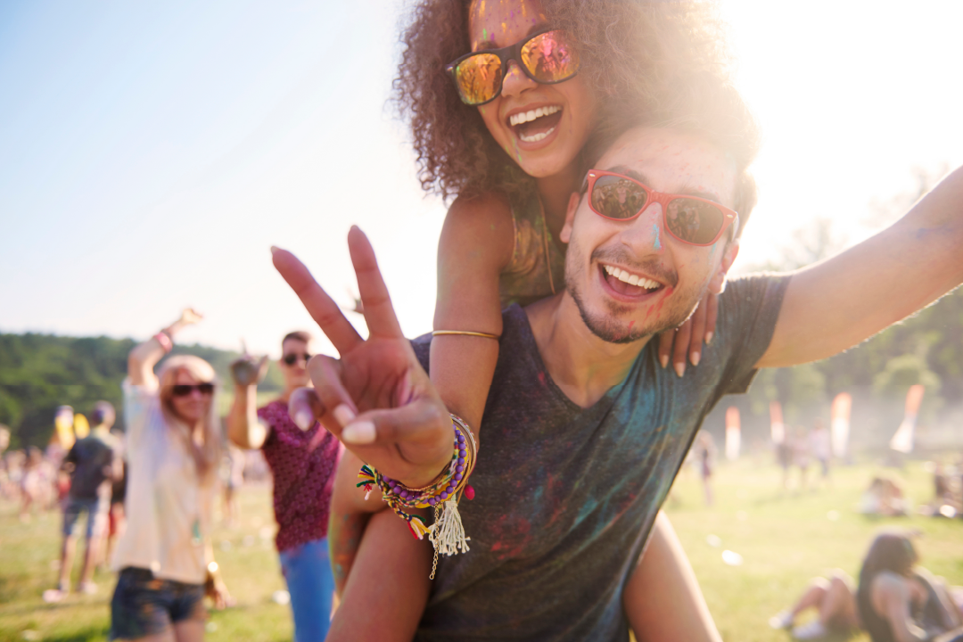 young adult couple enjoying music festival together with bright smiles