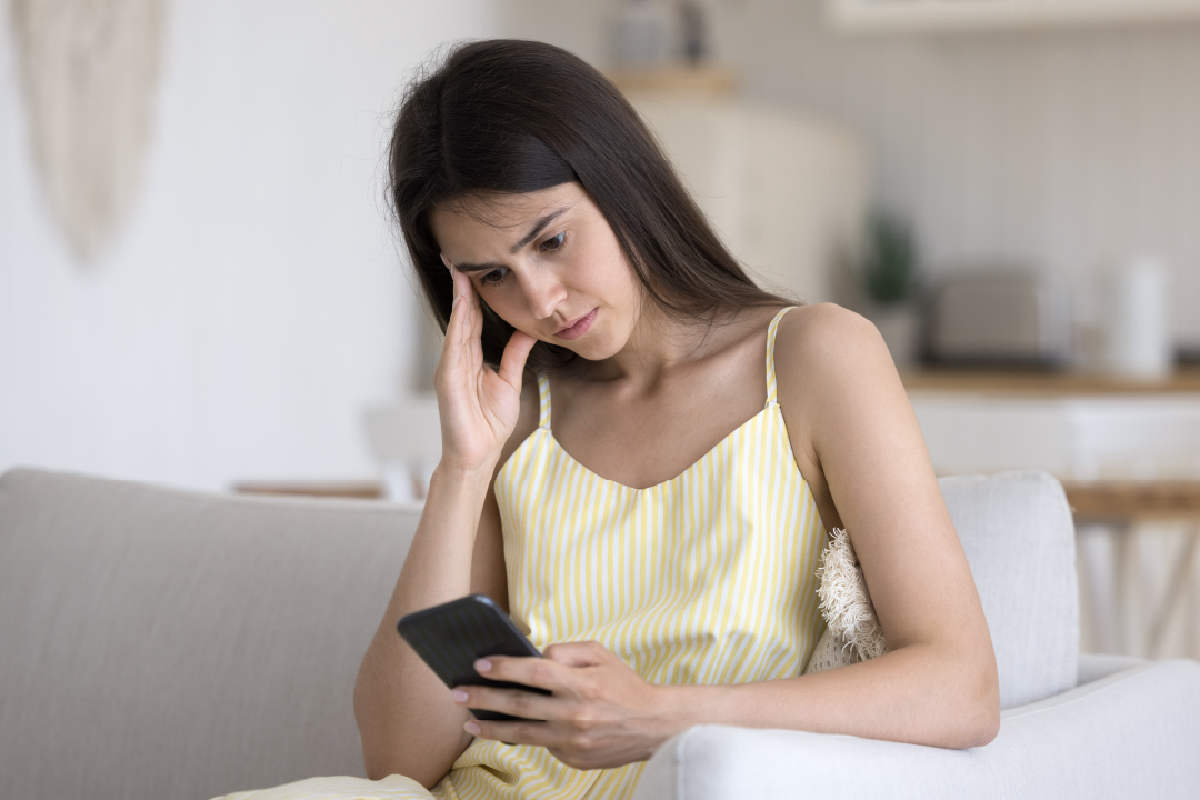 young adult female looking anxiously at her phone.