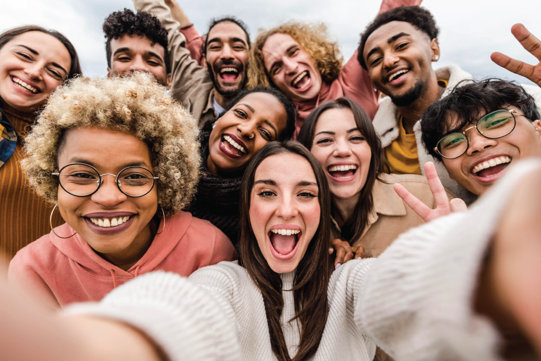 group of college aged adults gathered together for a group selfie taken by girl in center