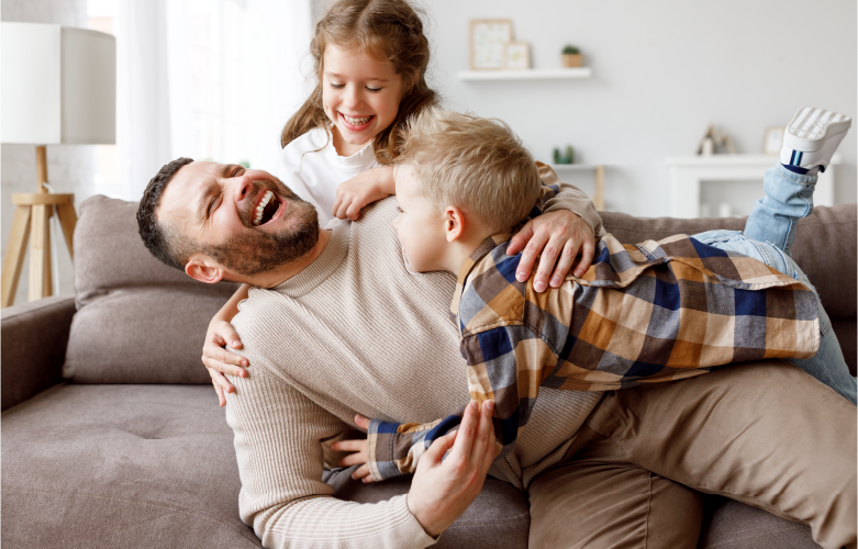 Father playing with two young children on the couch
