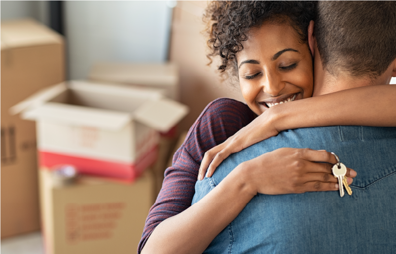 young adult couple hugging closely and holding keys as they move into new home