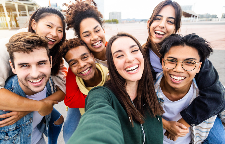 group of college students gathered outside in an group smiling and laughing together