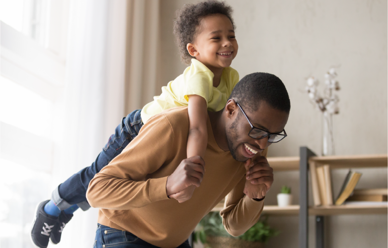 father carrying young son on his back both playing together