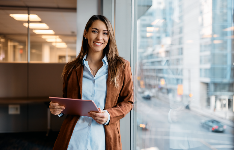 young adult professional smiling confidently while holding an iPad