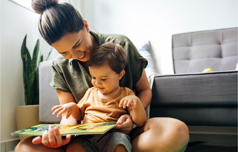 mother holding infant son in her lap reading together