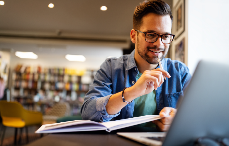 male college student studying in library with laptop